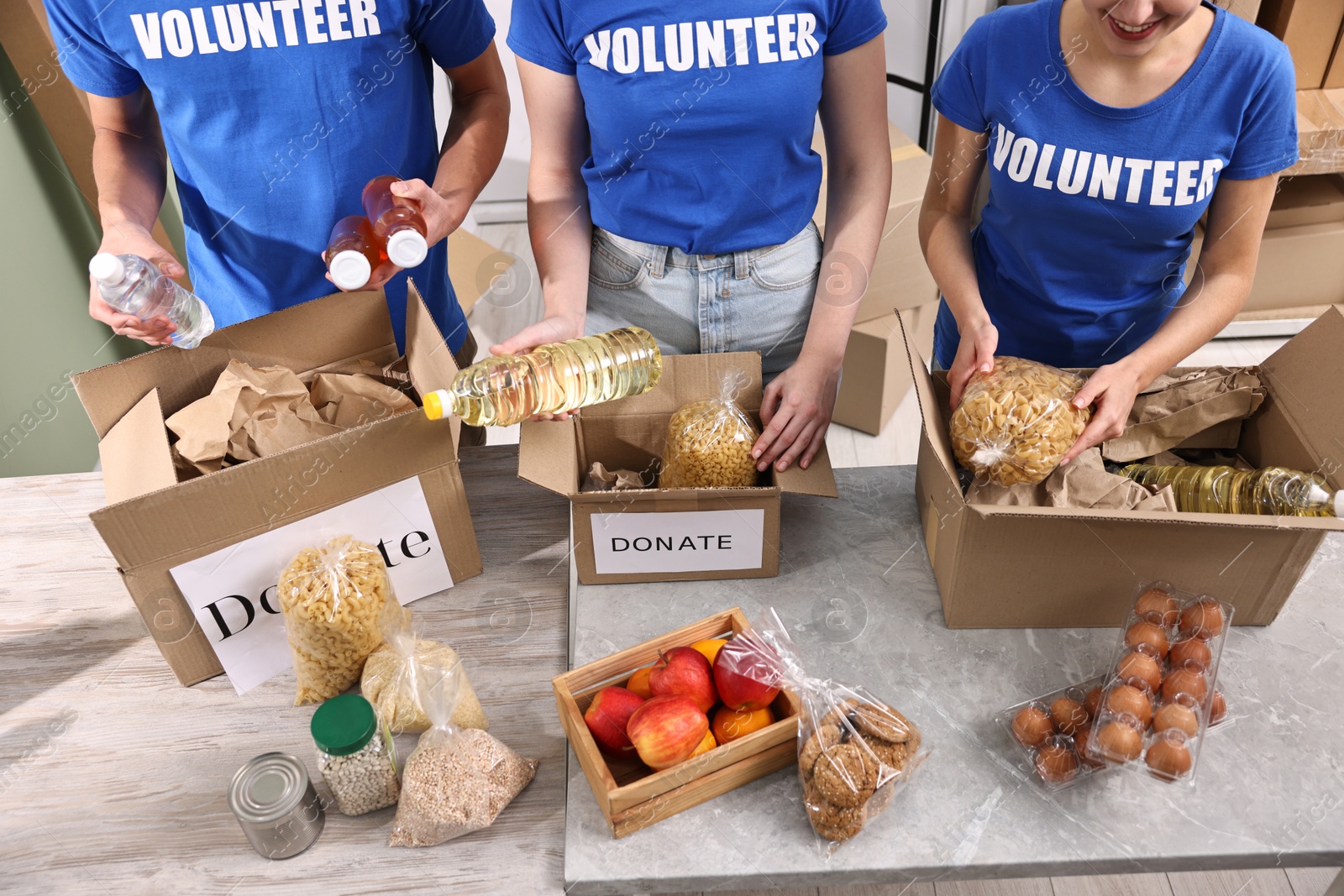 Photo of Volunteers packing food donations at tables indoors, closeup