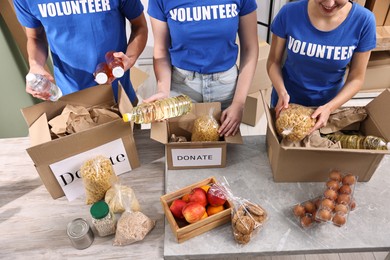 Photo of Volunteers packing food donations at tables indoors, closeup