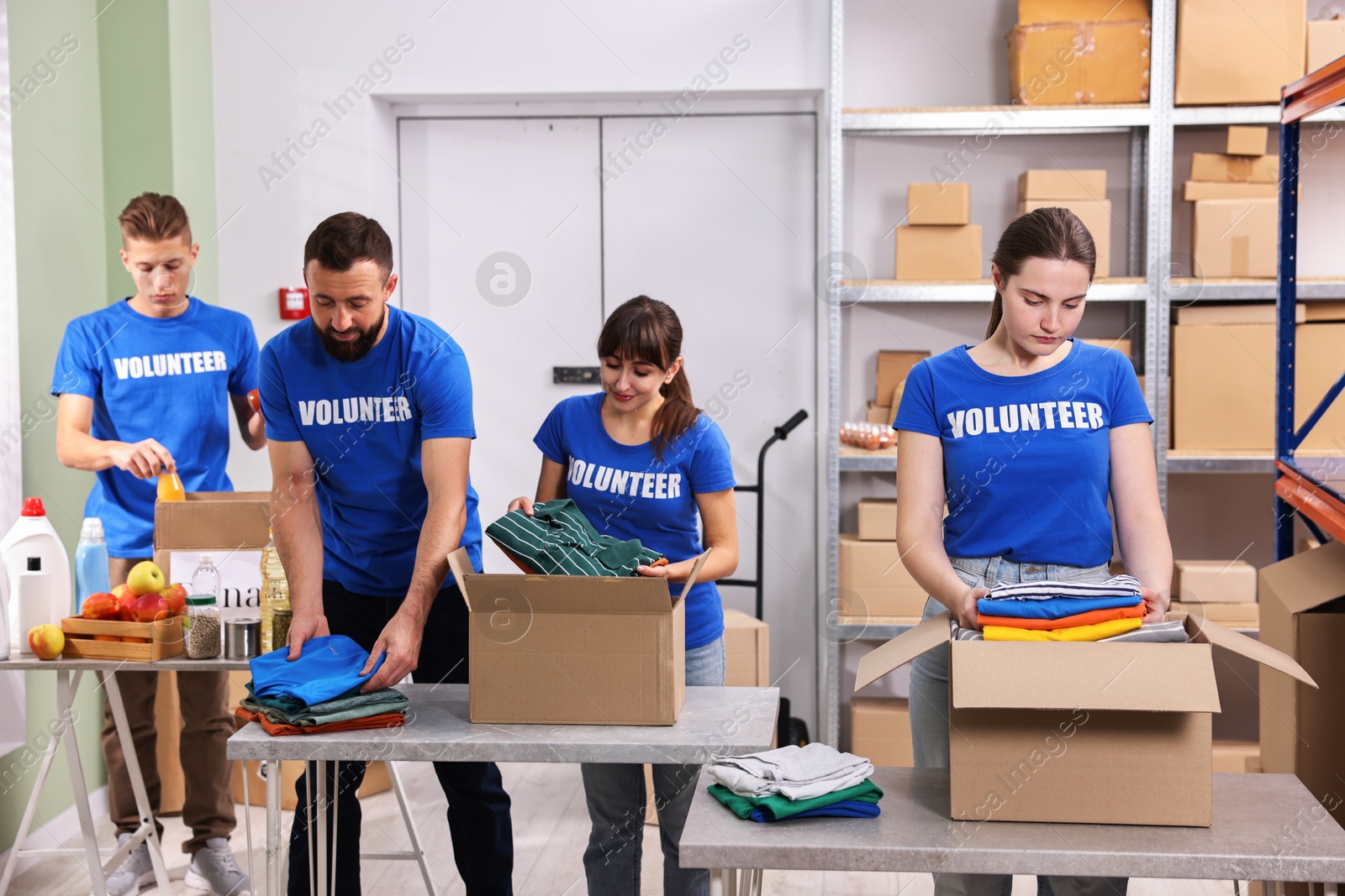 Photo of Group of volunteers packing donation goods at tables indoors