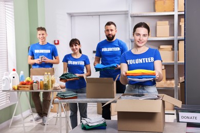 Photo of Group of volunteers packing donation goods at tables indoors