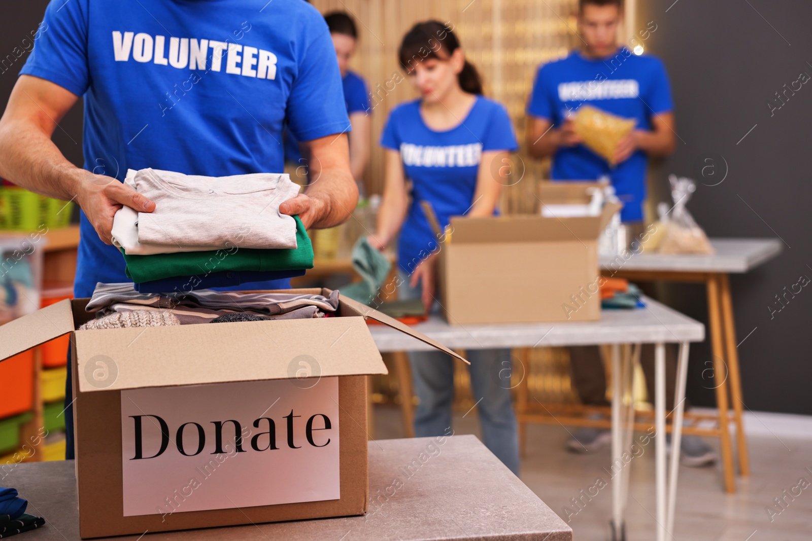 Photo of Volunteer putting clothes into donation box indoors, closeup