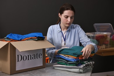 Photo of Volunteer sorting clothes for donation at table indoors