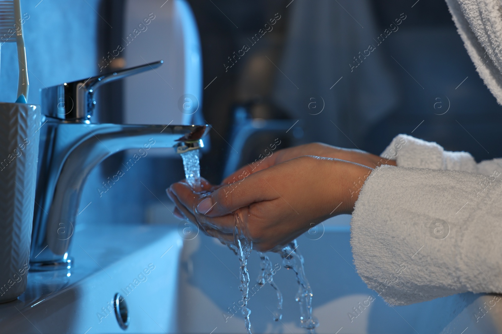 Photo of Woman washing her face over sink in bathroom, closeup