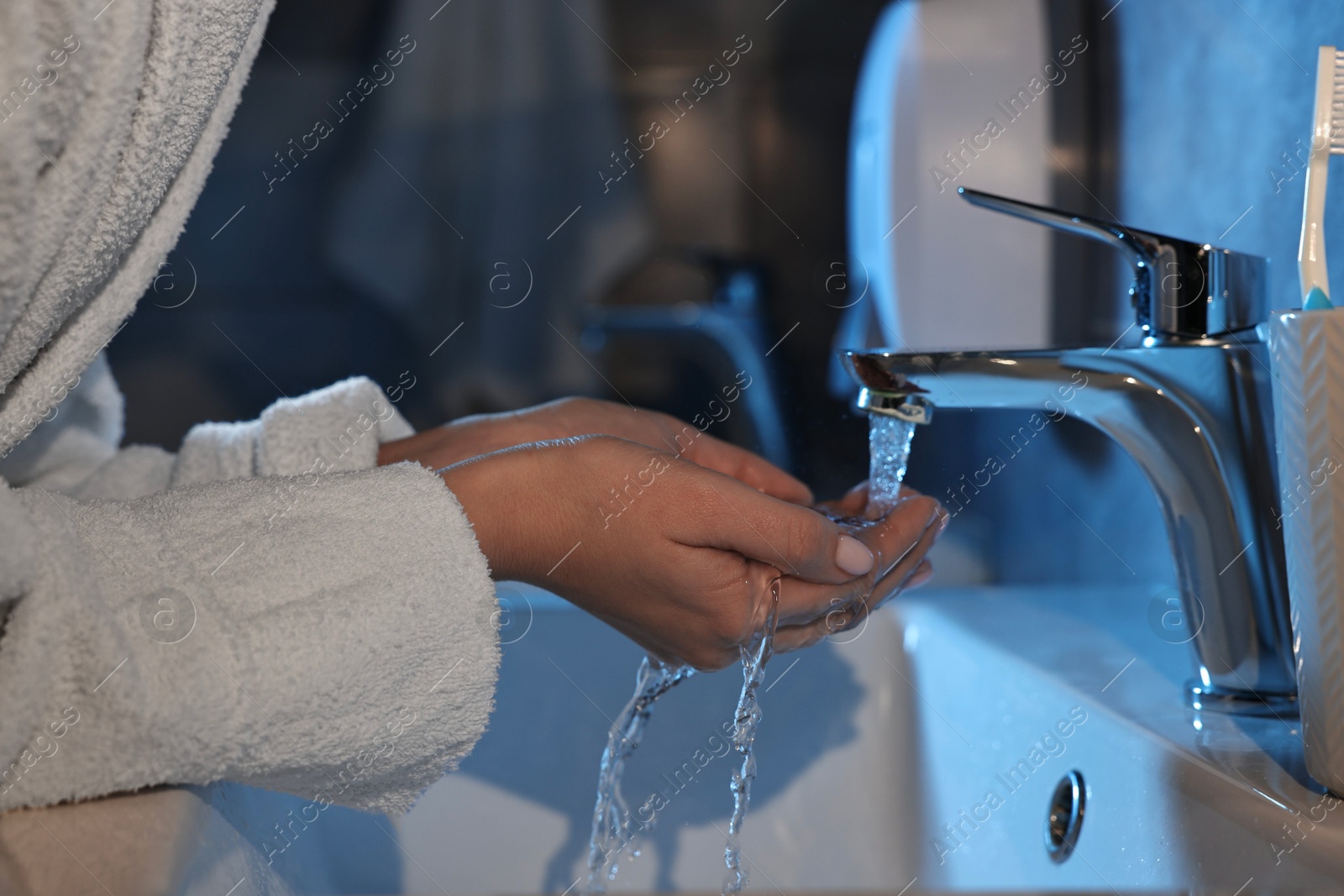 Photo of Woman washing her face over sink in bathroom, closeup