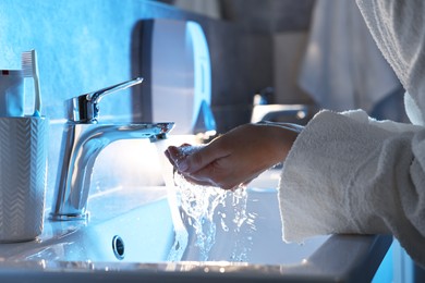 Photo of Woman washing her face over sink in bathroom, closeup