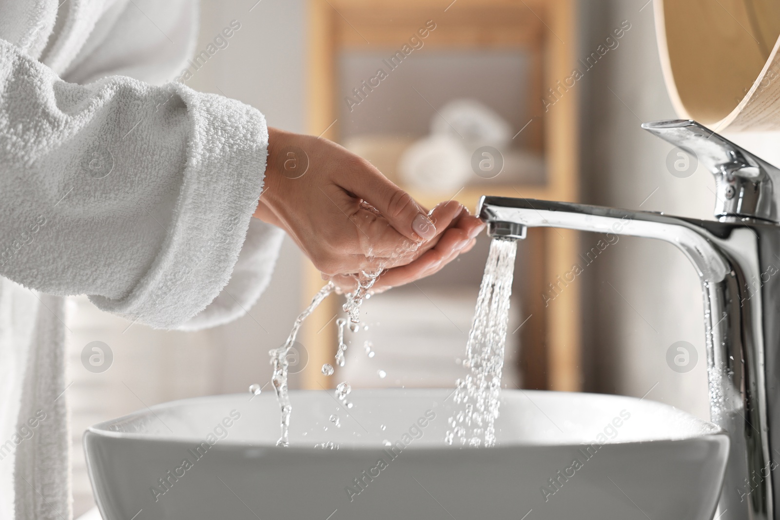 Photo of Woman washing her face over sink in bathroom, closeup