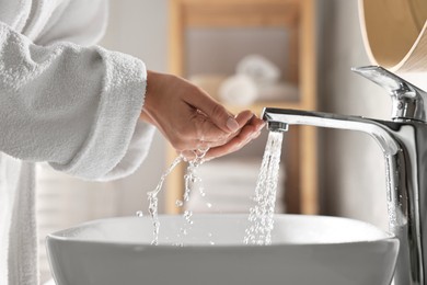 Photo of Woman washing her face over sink in bathroom, closeup