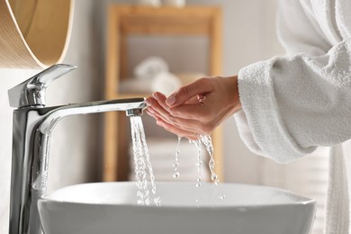 Photo of Woman washing her face over sink in bathroom, closeup