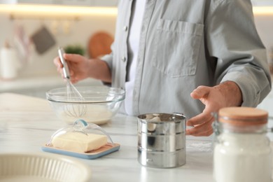 Photo of Man making dough at white marble table in kitchen, closeup