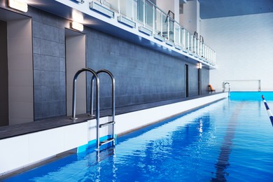 Photo of Swimming pool with clean water and ladder indoors