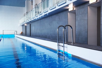 Photo of Swimming pool with clean water and ladder indoors