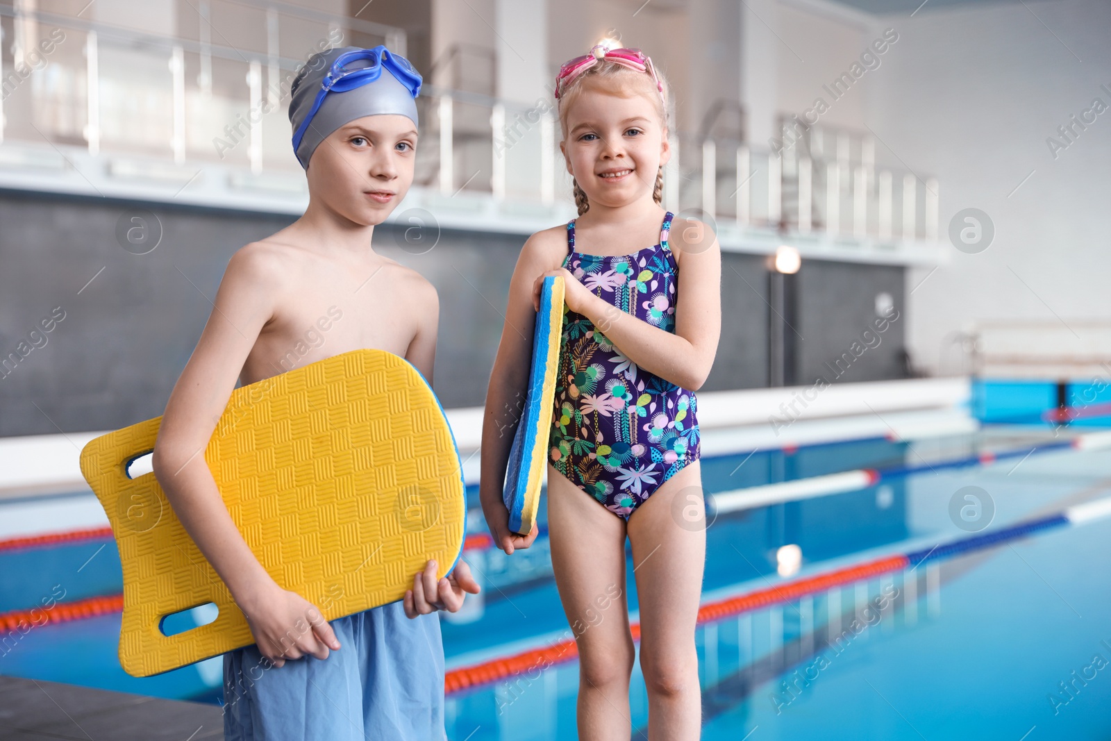 Photo of Children with goggles and kickboards near swimming pool indoors