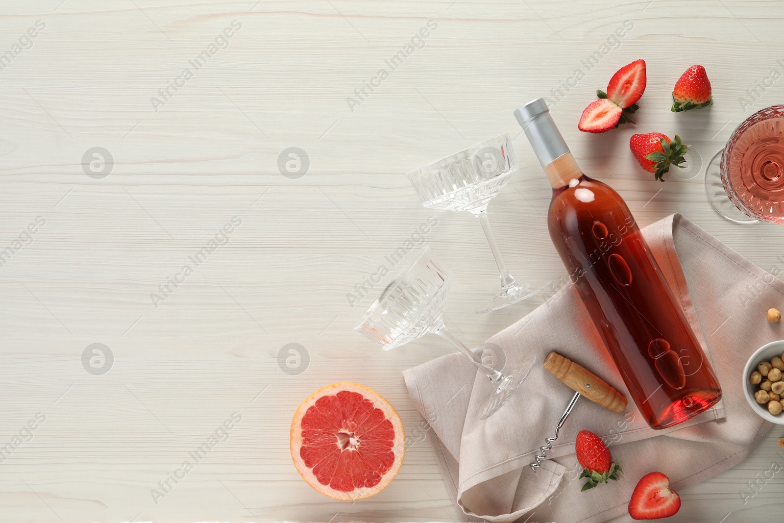 Photo of Flat lay composition with tasty rose wine, strawberries and grapefruit on light wooden table. Space for text