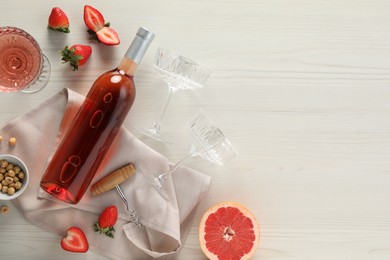 Photo of Flat lay composition with tasty rose wine, strawberries and grapefruit on light wooden table. Space for text