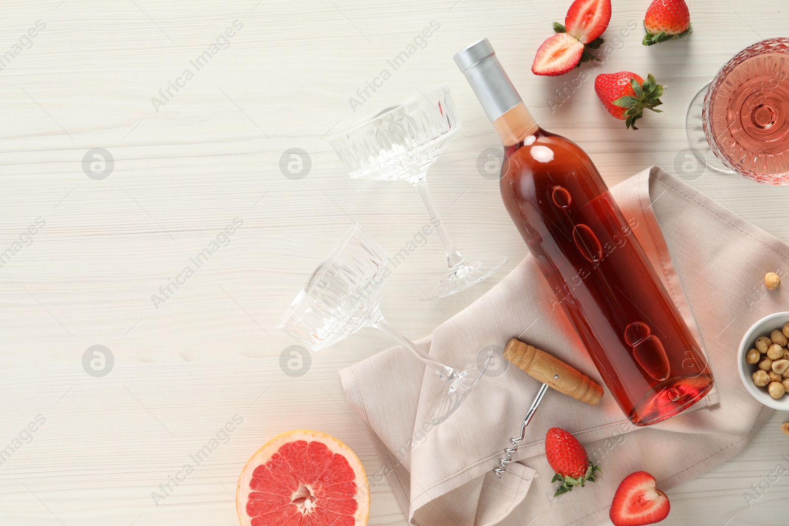 Photo of Flat lay composition with tasty rose wine, strawberries and grapefruit on light wooden table. Space for text