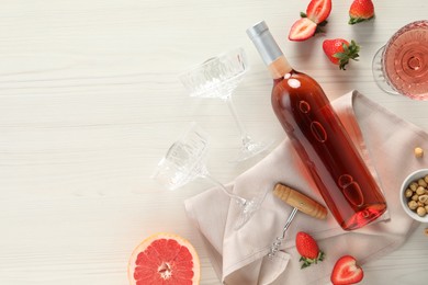 Flat lay composition with tasty rose wine, strawberries and grapefruit on light wooden table. Space for text