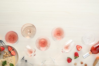 Photo of Flat lay composition with tasty rose wine and different food on light wooden table. Space for text