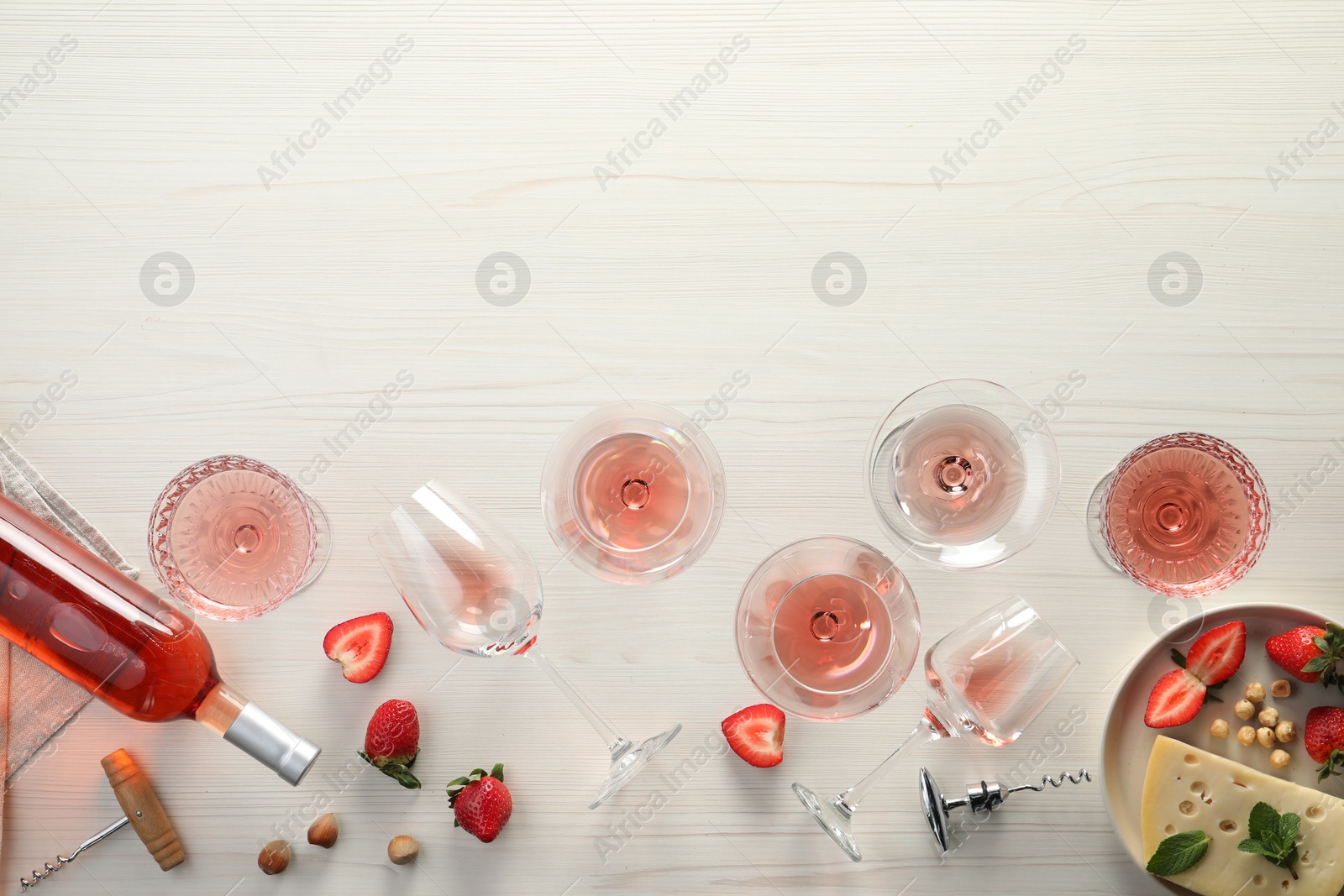 Photo of Flat lay composition with tasty rose wine and different food on light wooden table. Space for text