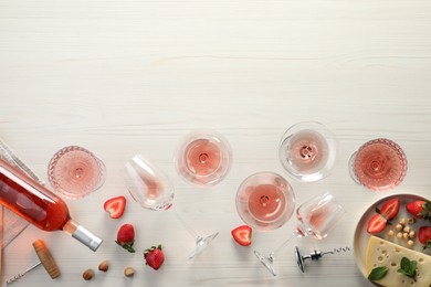 Flat lay composition with tasty rose wine and different food on light wooden table. Space for text