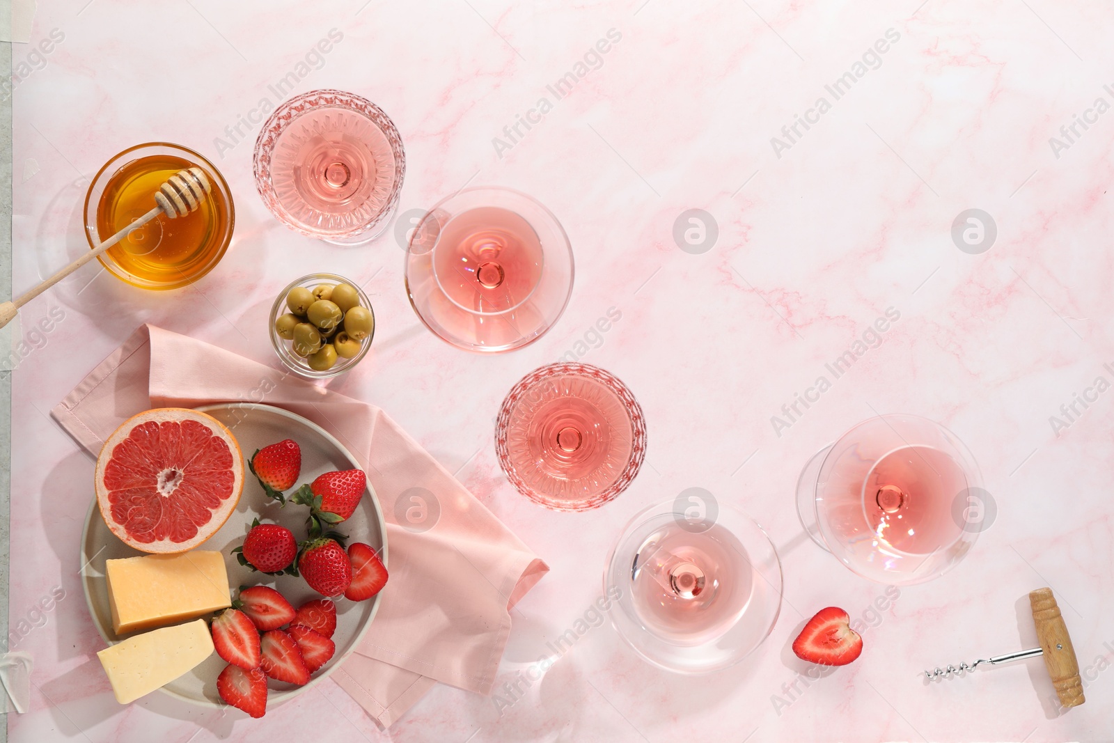 Photo of Flat lay composition with tasty rose wine and different food on pink marble table. Space for text