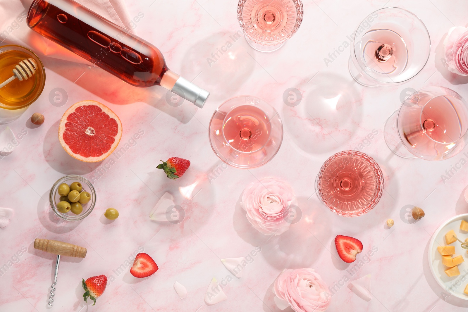 Photo of Flat lay composition with tasty rose wine and different food on pink marble table