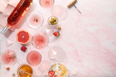 Photo of Flat lay composition with tasty rose wine and different food on pink marble table. Space for text