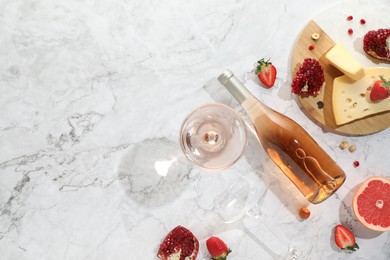 Flat lay composition with tasty rose wine and snacks on white marble table. Space for text