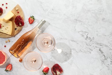 Flat lay composition with tasty rose wine and snacks on white marble table. Space for text