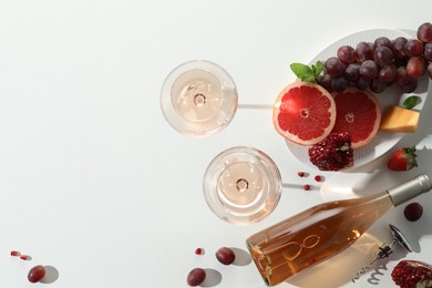 Photo of Flat lay composition with tasty rose wine and snacks on white table. Space for text