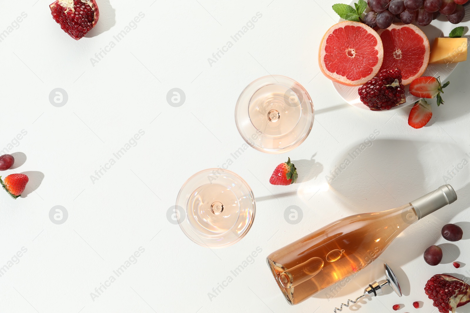 Photo of Flat lay composition with tasty rose wine and snacks on white table. Space for text