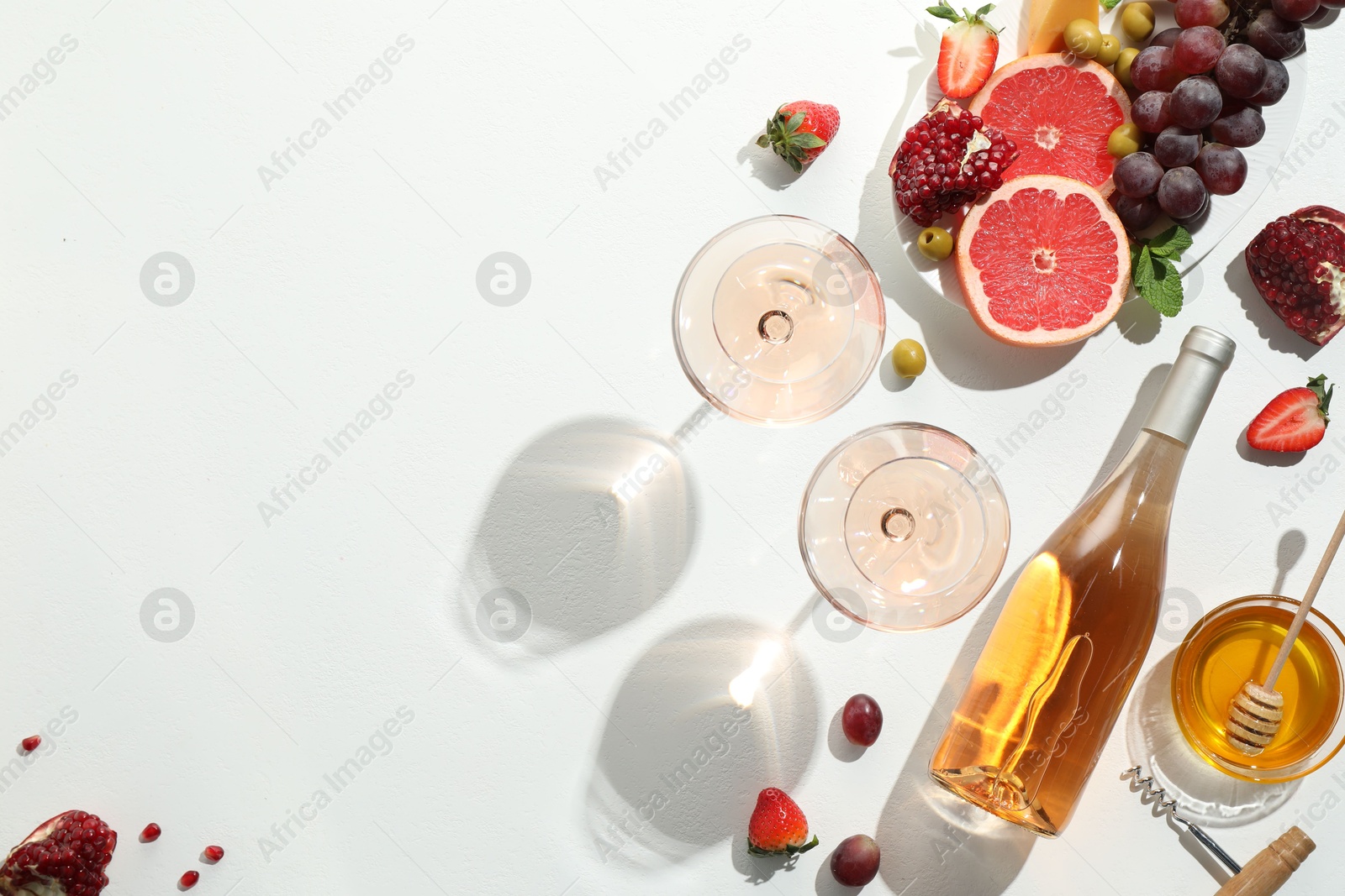 Photo of Flat lay composition with tasty rose wine and snacks on white table. Space for text