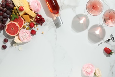 Flat lay composition with tasty rose wine and snacks on white marble table. Space for text