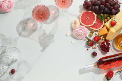 Flat lay composition with tasty rose wine and snacks on white marble table. Space for text