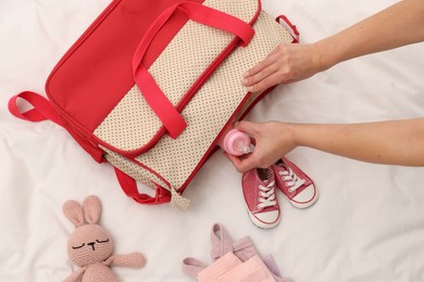 Photo of Mother packing baby's stuff into bag on bed, above view