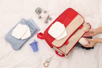 Photo of Mother packing baby's stuff into bag on bed, above view