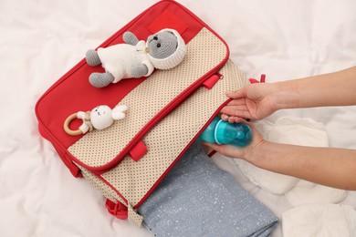 Photo of Mother packing baby's stuff into bag on bed, above view