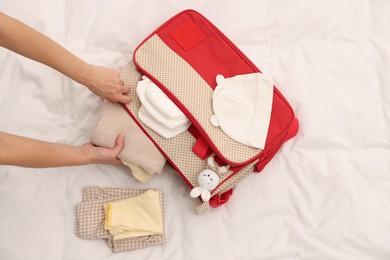 Photo of Mother packing baby's stuff into bag on bed, above view