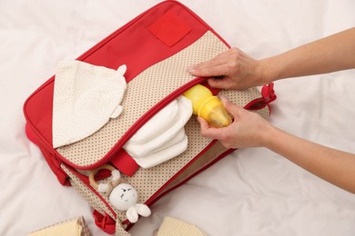 Photo of Mother packing baby's stuff into bag on bed, above view