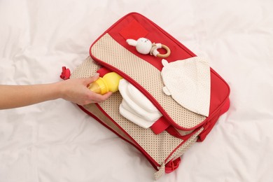 Photo of Mother packing baby's stuff into bag on bed, above view