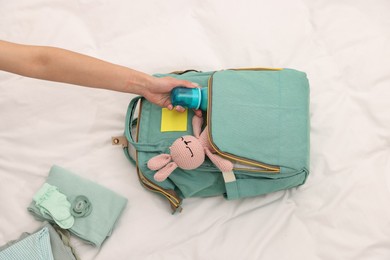 Photo of Mother packing baby's stuff into bag on bed, above view