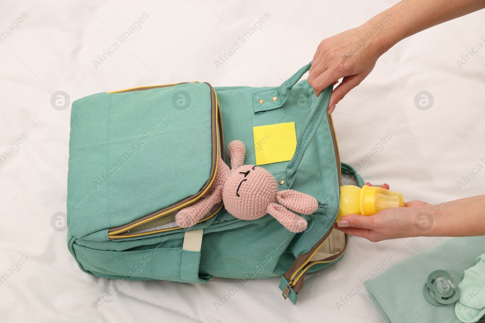 Photo of Mother packing baby's stuff into bag on bed, above view