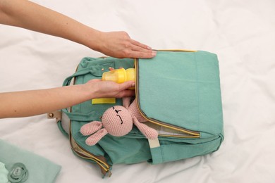 Photo of Mother packing baby's stuff into bag on bed, above view