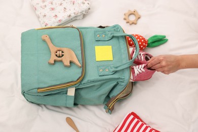 Photo of Mother packing baby's stuff into bag on bed, above view