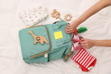 Photo of Mother packing baby's stuff into bag on bed, above view