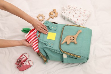 Photo of Mother packing baby's stuff into bag on bed, above view