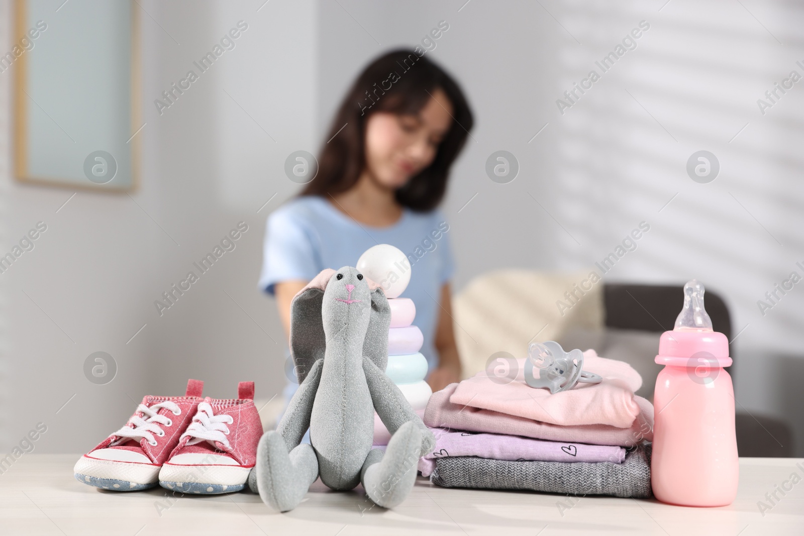 Photo of Baby's stuff on white table and mother packing bag, selective focus