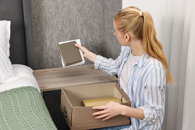 Photo of Female decorator arranging books onto nightstand indoors