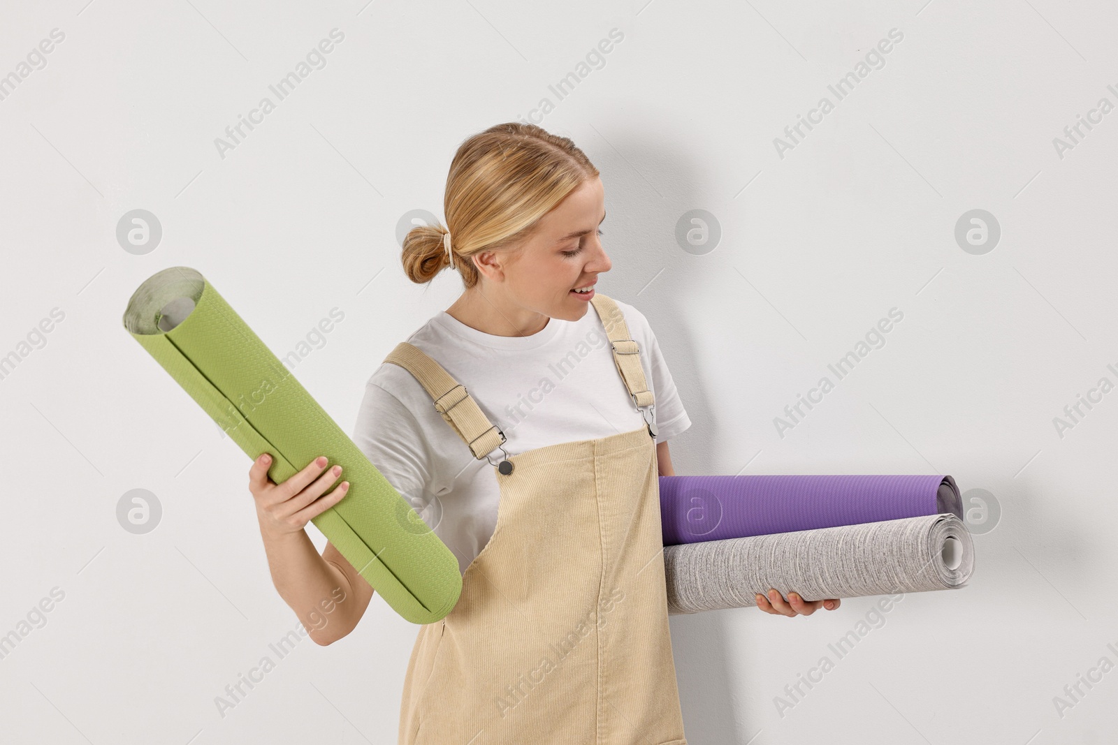 Photo of Smiling worker with rolls of wallpapers indoors