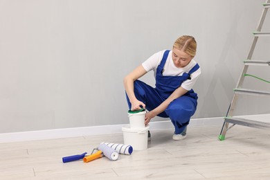 Photo of Female worker preparing to painting wall indoors