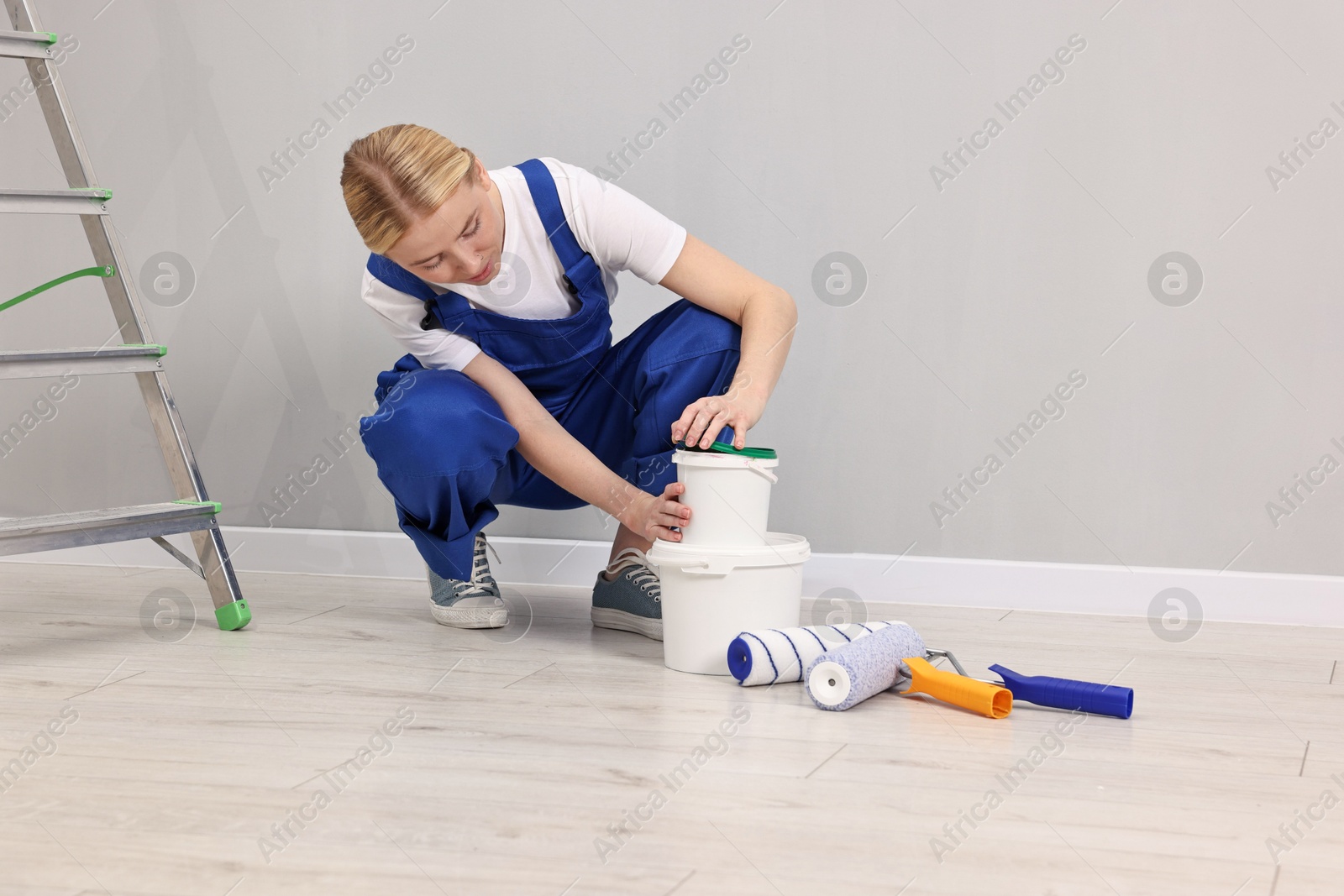 Photo of Female worker preparing to painting wall indoors